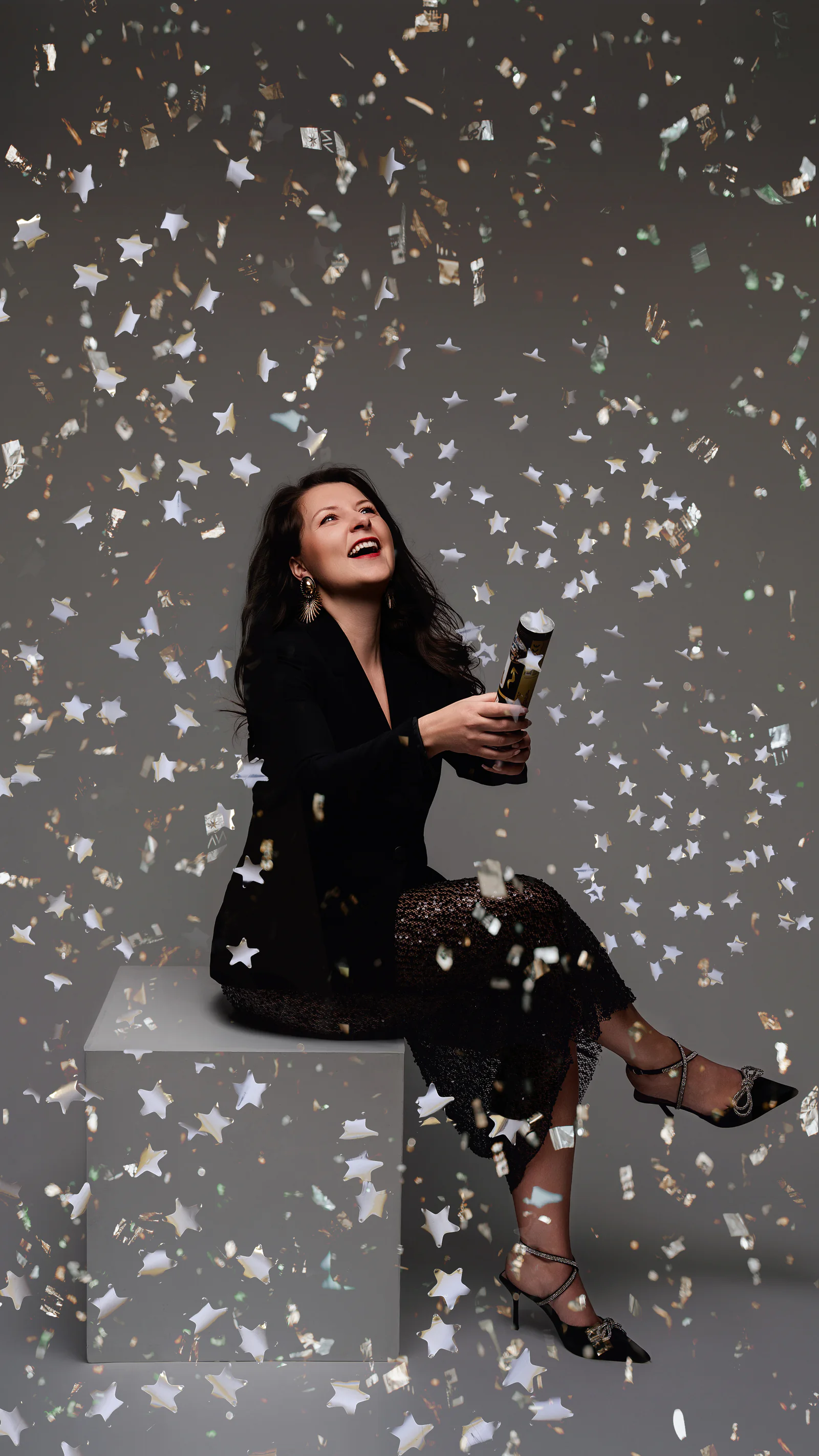 Portret editorial așezat, surprins printre confetti în formă de stele.