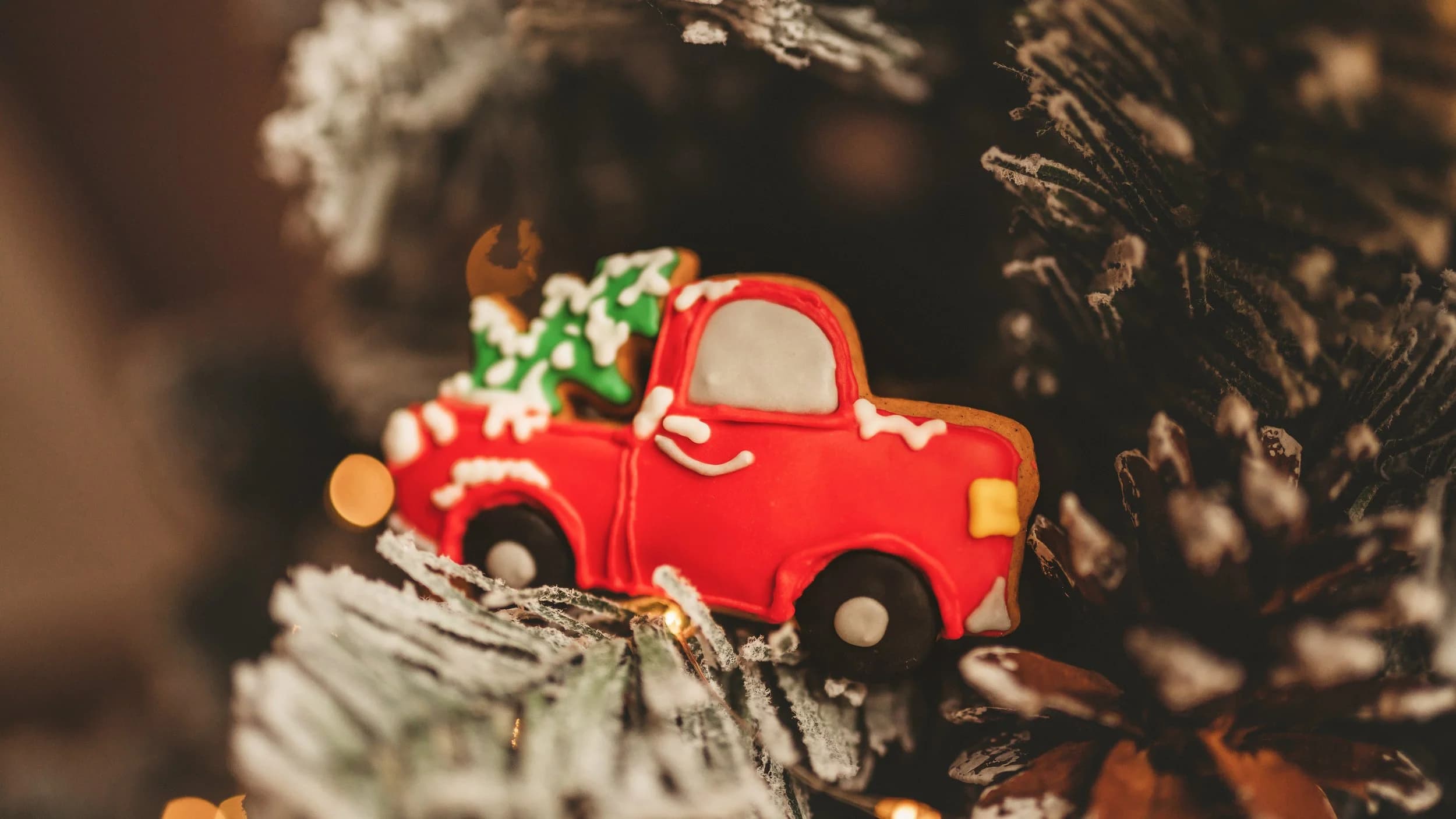 Prăjituri decorate de Crăciun alături de o camionetă roșie în miniatură