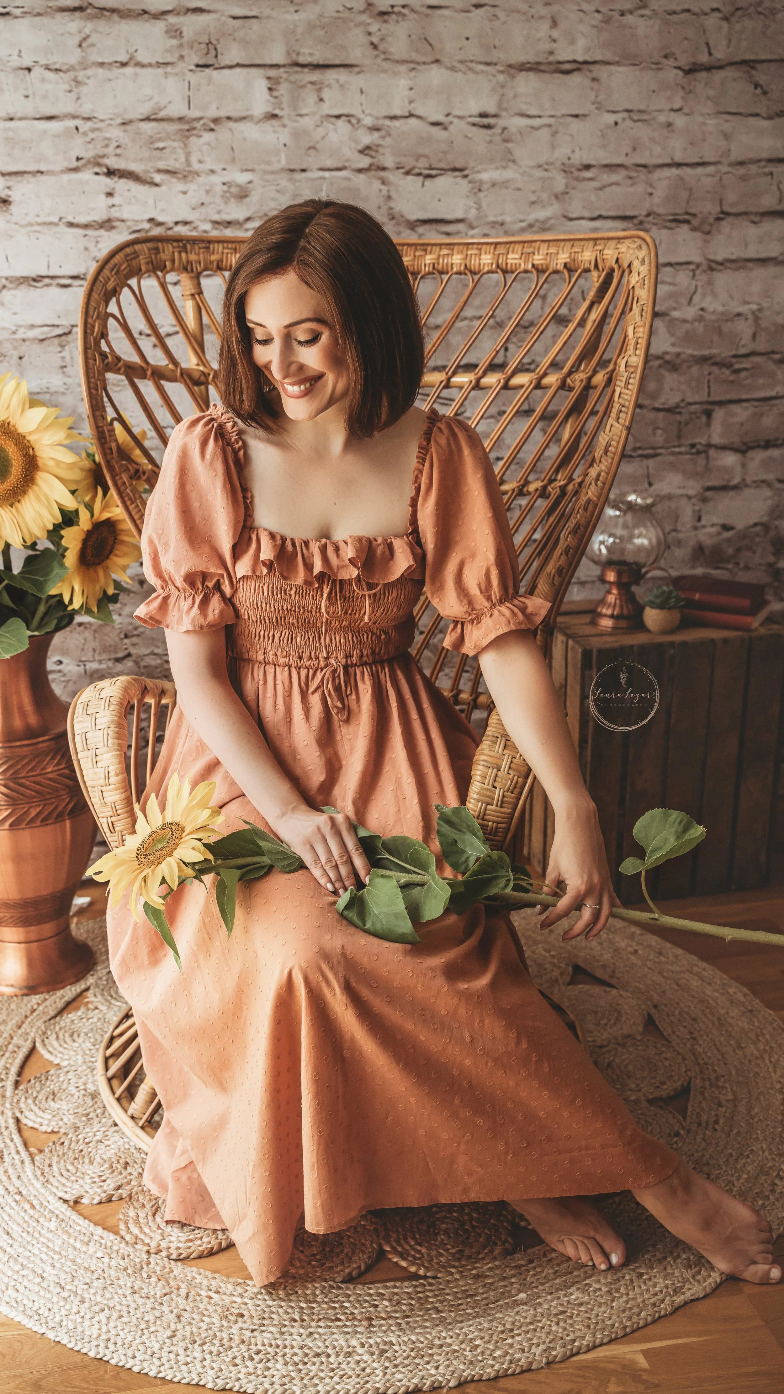 O femeie așezată lângă flori de floarea-soarelui într-un decor editorial cald